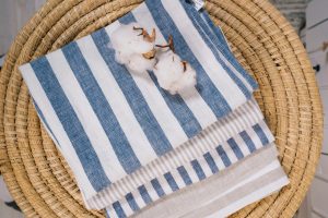Top view of striped linen towels with cotton flowers on a rattan surface.